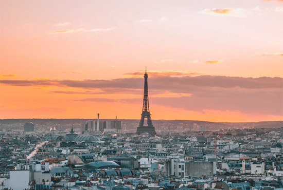Paris, France - aerial city view with Eiffel Tower at sunsetan rides bicycle on cobblestone street, volcanic mountain in background - photo by Edouard Grillot, unsplash.com/@edouard_grit